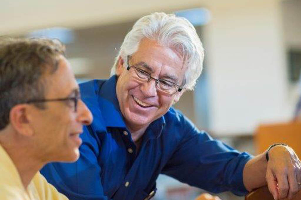 A men helping another men on a computer