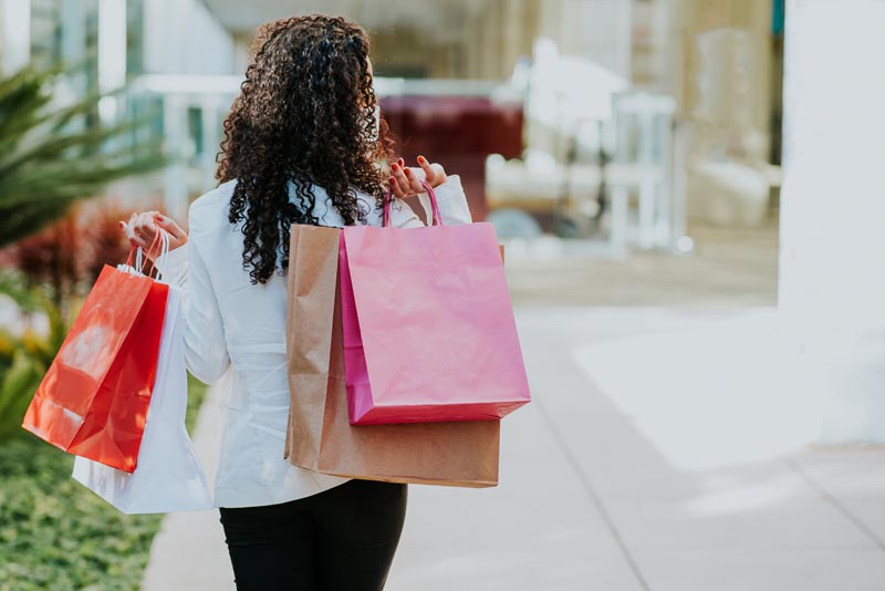 Women walking and holding four shopping bags on her shoulder