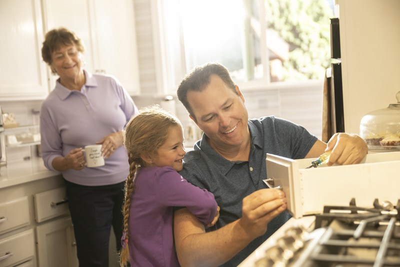 A man and a young girl are cooking together at a stove, sharing a moment of collaboration and learning in the kitchen.